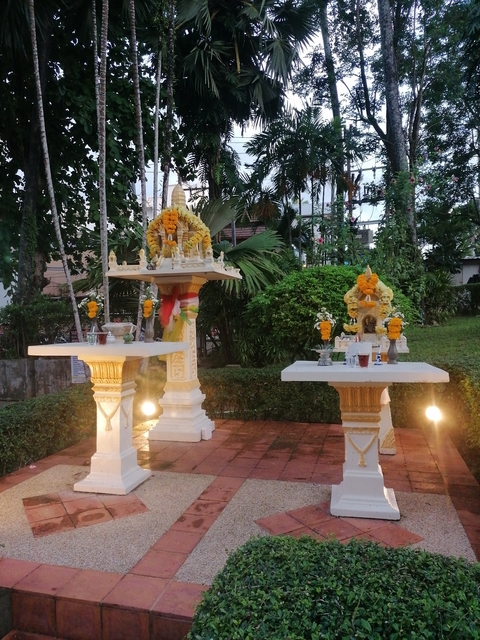 Thai spirit house with floral offerings.
