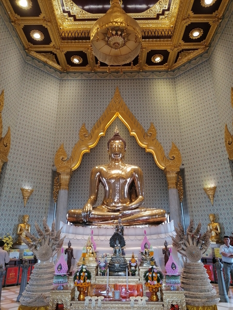 Golden Buddha statue inside a richly decorated temple.