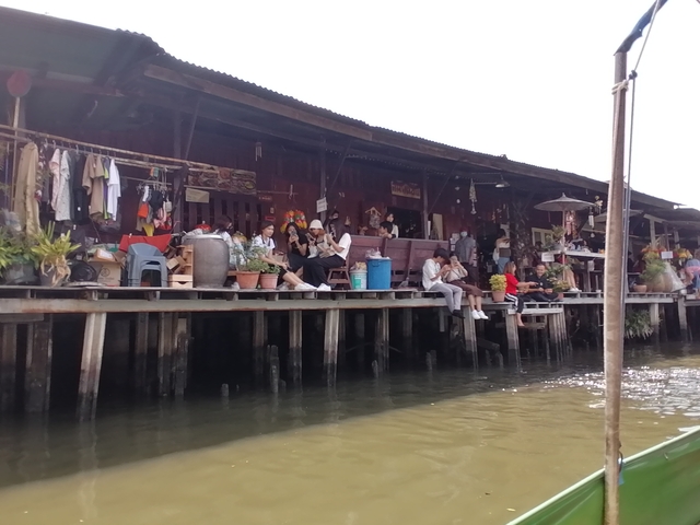 Floating market with people seated by the water.