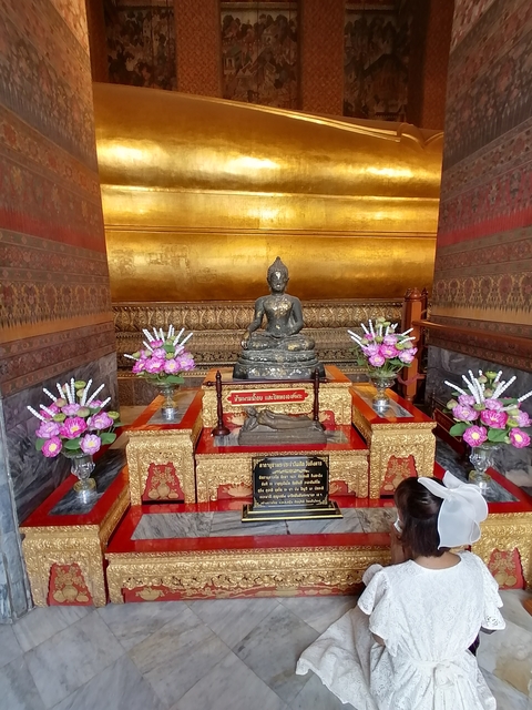 Temple interior with a statue and floral decorations.