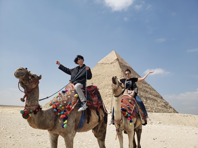Tourists on camels in front of a pyramid.