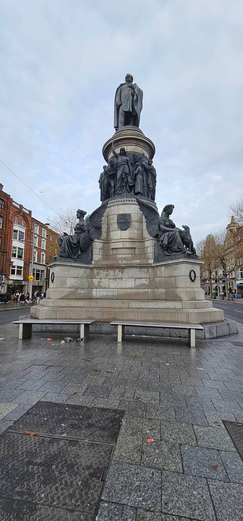 Monument with statues in a busy urban location.