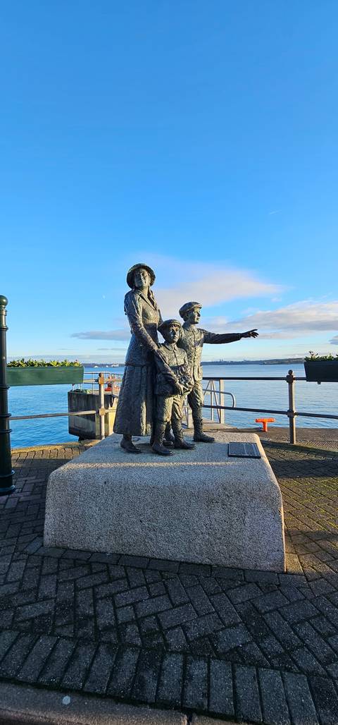 Statue by a waterfront with scenic skyline.