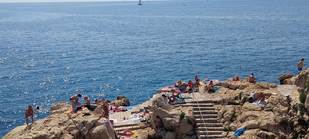 People relaxing on rocky beach by the sea.