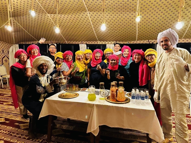Group of people in colorful attire enjoying tea.