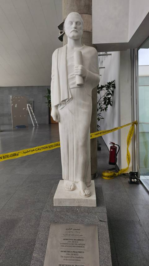 White statue placed indoors with caution tape and informational plaque.