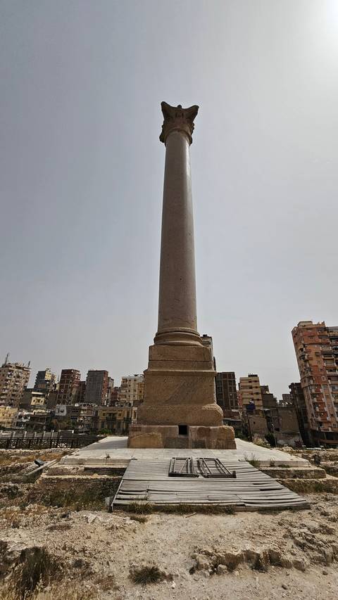 Tall column monument set against a cityscape.