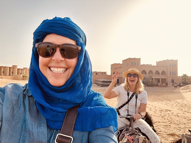 Two people smiling with desert architecture in the background.