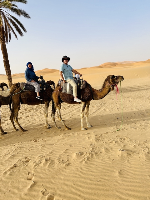 People riding camels in the desert.