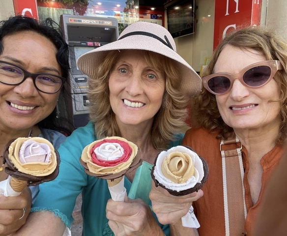 Three women holding ice cream cones shaped like flowers.
