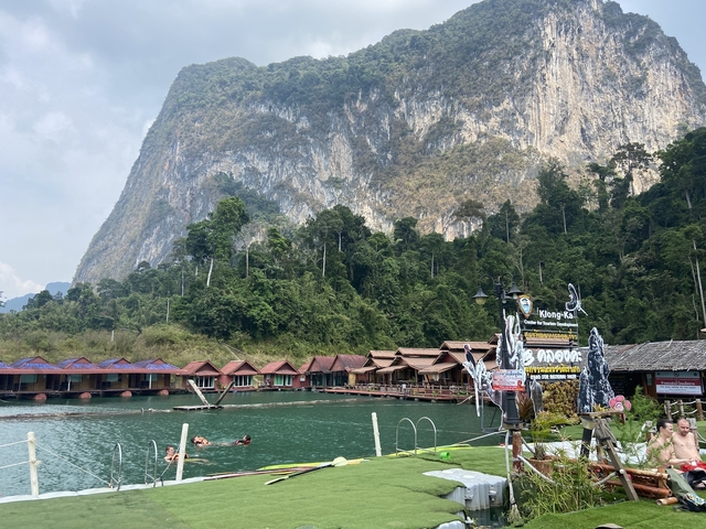 Floating huts on a lake with a mountainous backdrop.