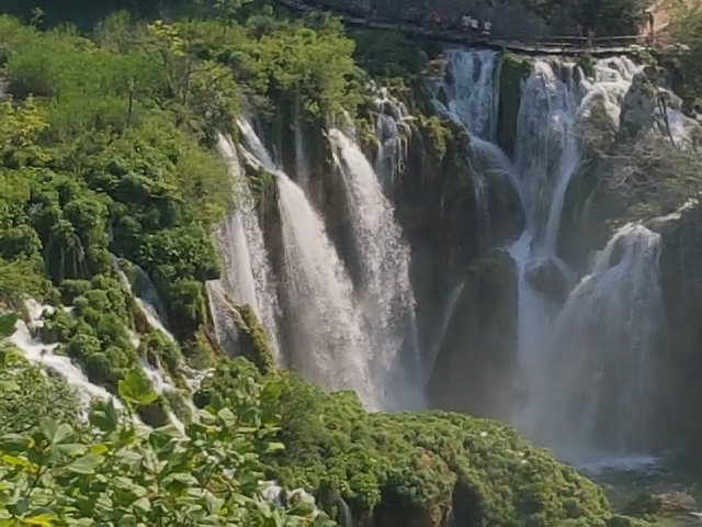 Blurry waterfall scene surrounded by greenery.