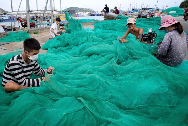 People working with fishing nets on a dock.