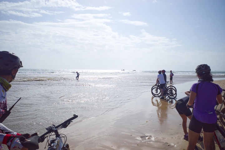 Cyclists at a beach during low tide.