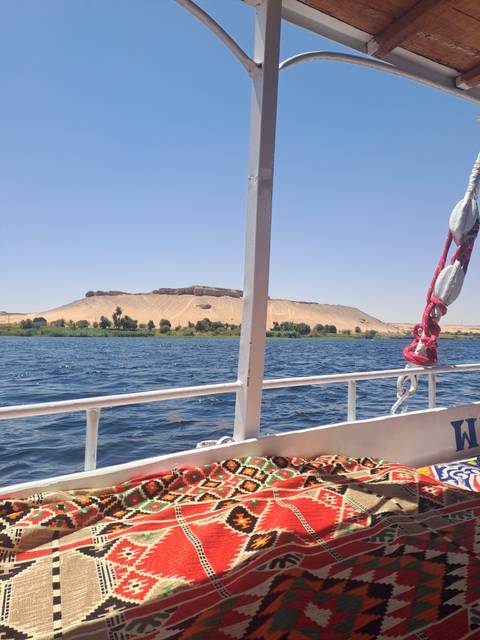 Colorful patterned textile on a boat with a water and desert backdrop.