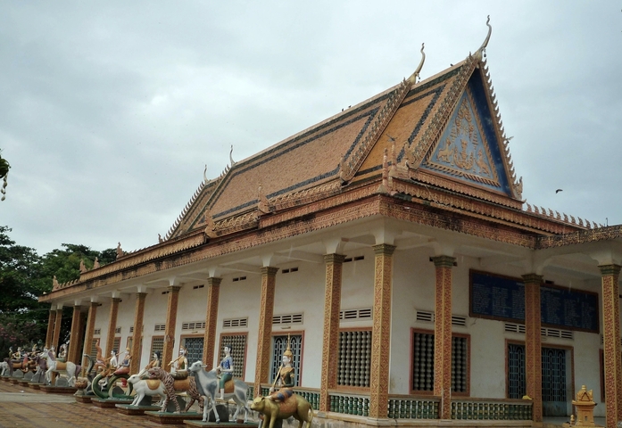 Intricately designed temple with statues and cloudy sky.