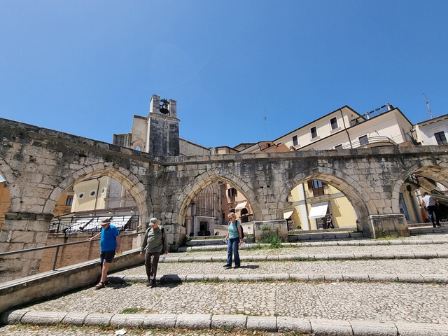 Stone archway with people and buildings around
