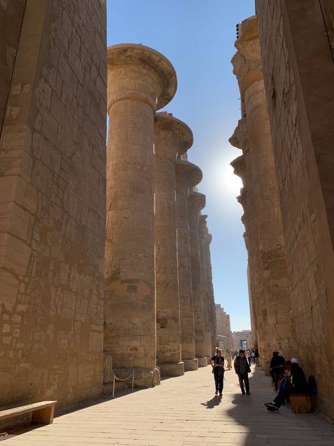 A view of ancient columns with people walking around.