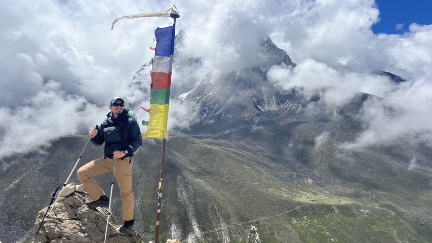 A person with prayer flags and a mountain view.