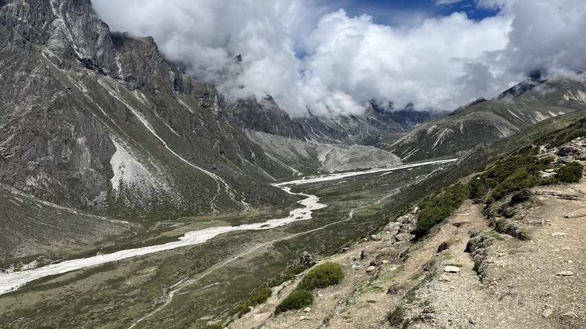 Mountain range with clouds and a winding glacial river.