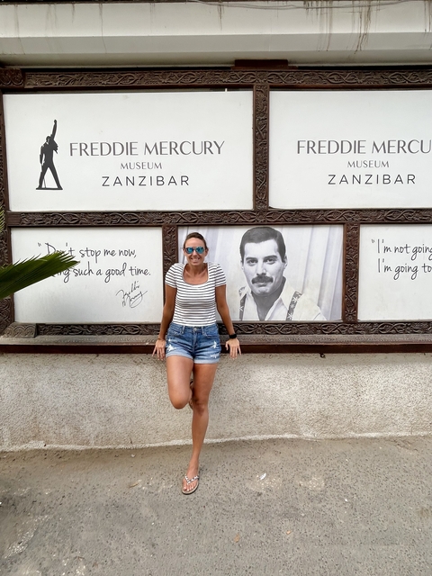 Woman posing in front of a mural with the word Zanzibar.