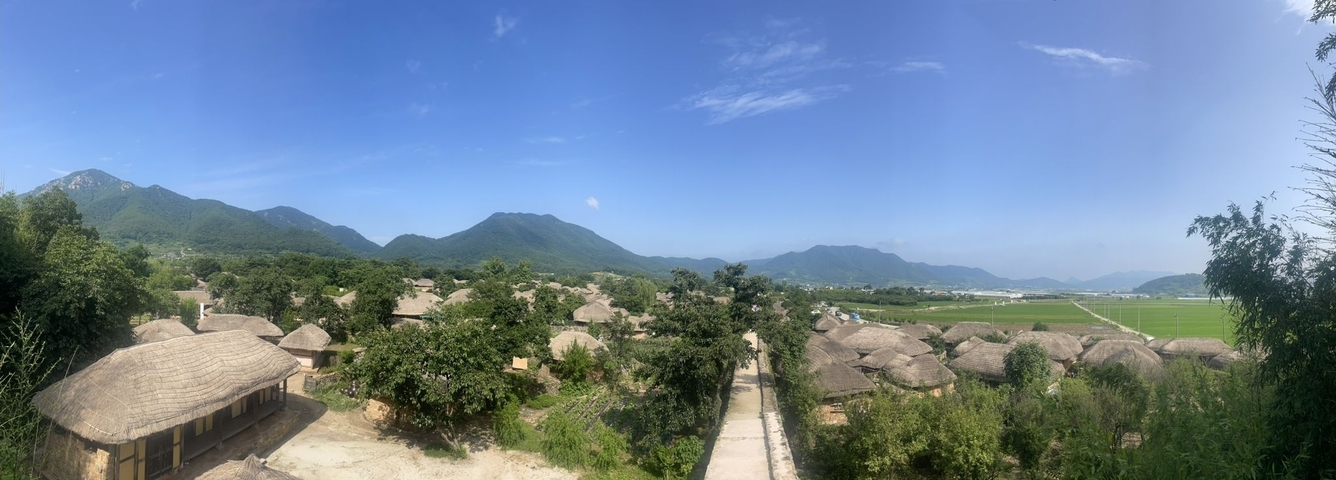 Panoramic view of traditional thatched roofs and mountains.
