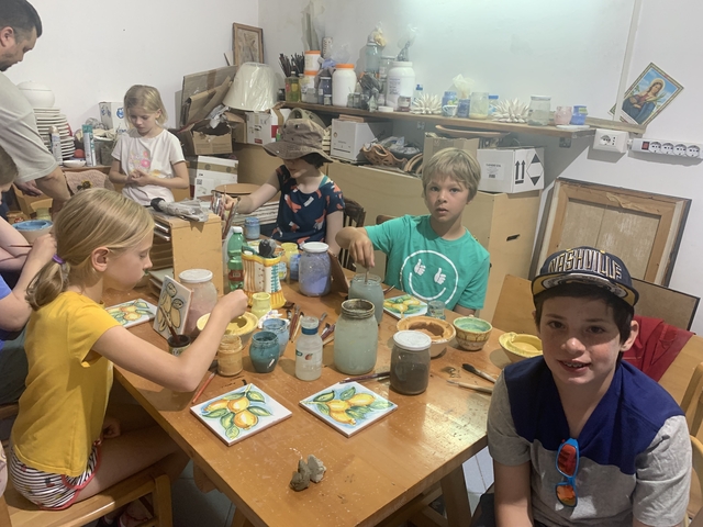 Kids painting ceramics at a workshop table.