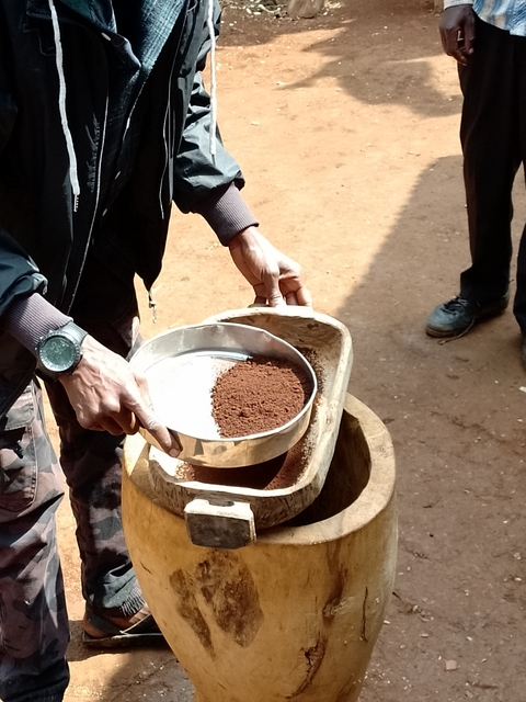 Person handling ground coffee in a bowl.