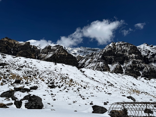 Snowy mountain landscape with rugged peaks under a blue sky.