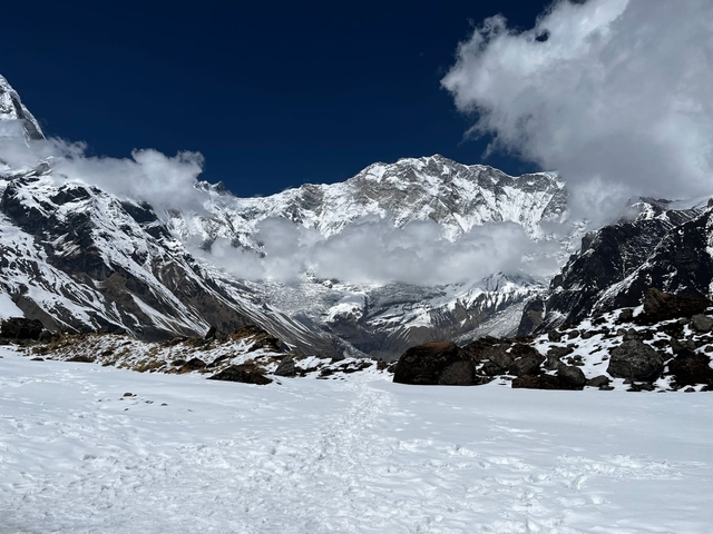 Snowy mountain range with clouds partially covering peaks.