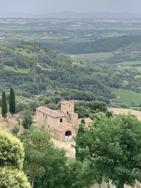 Rural landscape with a rustic stone building surrounded by greenery.