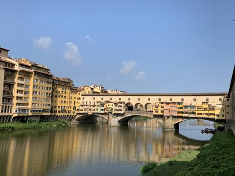 Ponte Vecchio bridge with buildings reflected in the river.
