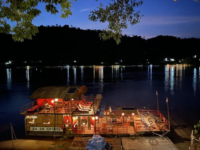 Riverside view with a lit boat and reflections on the water.