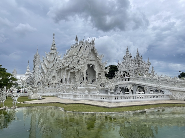 Intricately detailed white temple reflected in a pond.