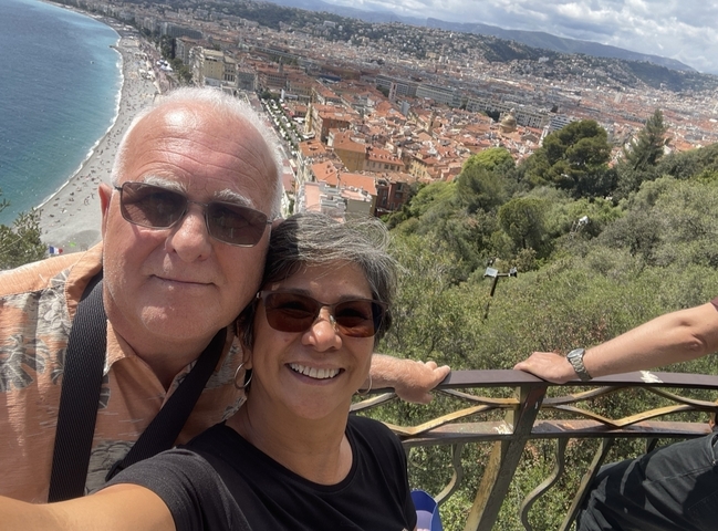 Selfie of a couple with a panoramic view of a coastal city.