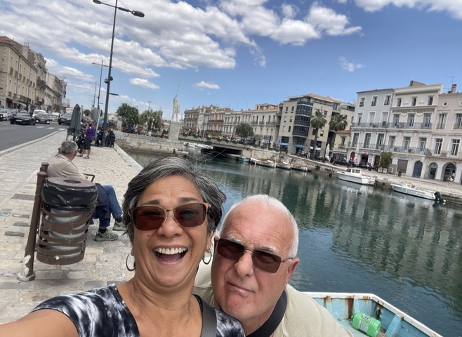 Couple taking a selfie by a scenic waterfront in a European city.