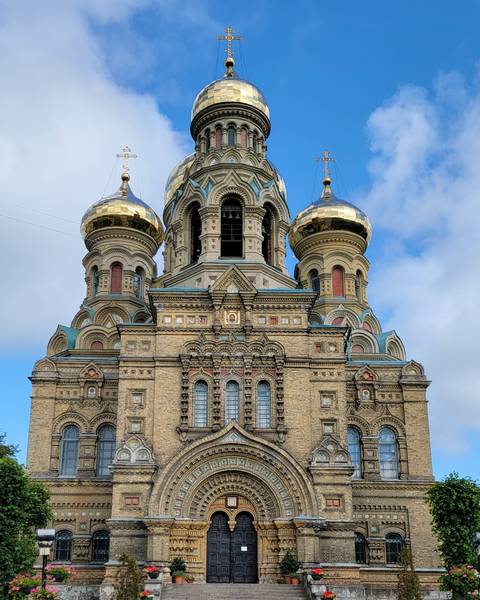 An ornate church with golden domes under a clear sky.