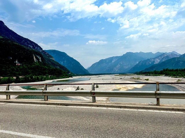 A river with mountains in the background seen from a bridge.
