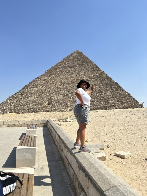 Person posing in front of a large pyramid.