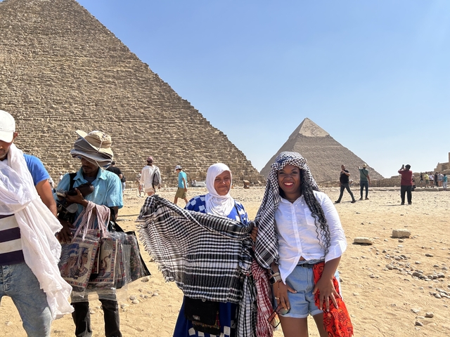 People in front of the Pyramids, some holding scarves.