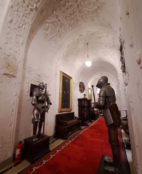 Interior of a museum featuring suits of armor and ornate hallways.