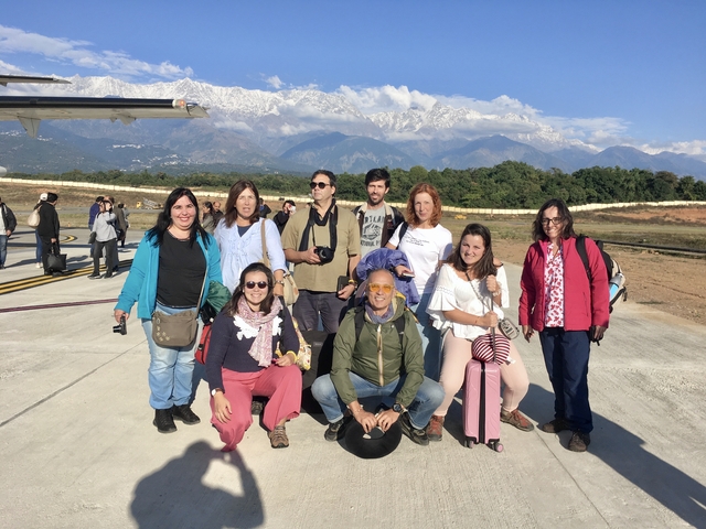 Group at an airport with snow-capped mountains.