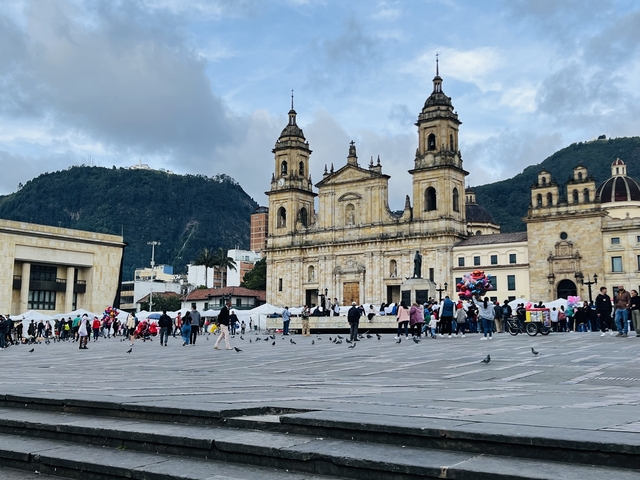 A bustling plaza in front of a historic cathedral with people and pigeons.