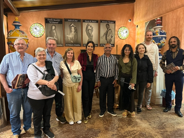 Group of people inside a colorful room with portraits on the wall.
