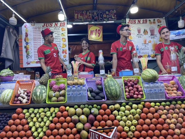 Fruit market stall with vendors in colorful attire.