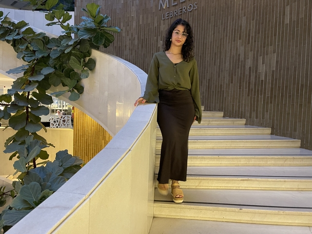 Person posing on indoor stairs with plants.