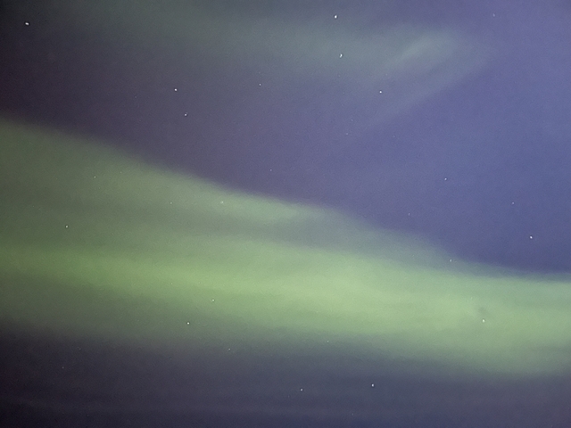 Green aurora borealis lights in the night sky.