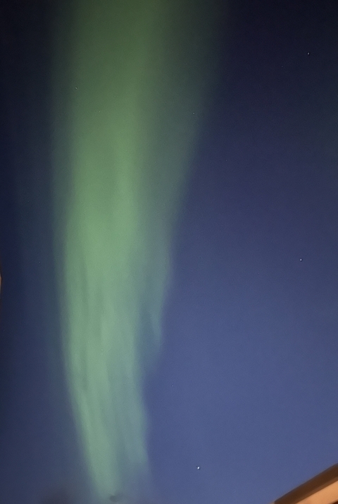 Green aurora borealis against a night sky.