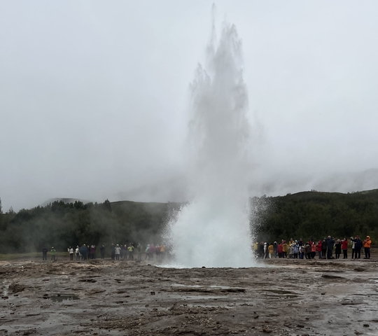 Geyser eruption with a crowd of spectators.