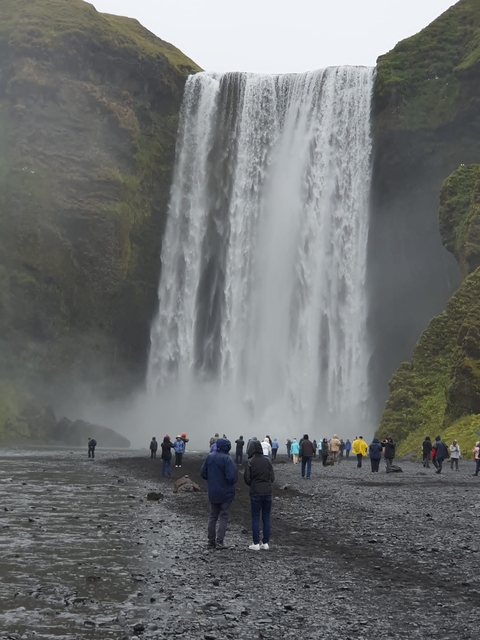 Large waterfall with a group of people standing below.